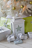 Sternförmige Laterne mit eingepackten Geschenken unter dem Weihnachtsbaum in einem Einfamilienhaus im Süden Londons England UK