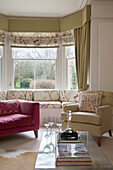 Pink and cream armchairs with window seat in Gloucestershire home England UK