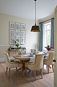 Cream upholstered dining chairs with brass pendant light in Worcestershire home England UK
