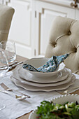 Serviette gefaltet in weißer Keramikschleife auf einem gedeckten Tisch in Worcestershire, England, UK
