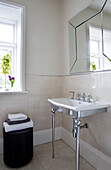 Gefaltete Handtücher auf einem Hocker mit Waschbecken und Spiegel in einem Badezimmer in Worcestershire, England, UK