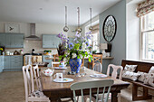 Cut flowers on wooden table with painted chairs in open plan Kelso kitchen Scotland UK