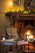 Wicker chair at lit fireside with fairylights in Hampshire farmhouse England UK