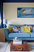 Gemischte Kissen auf hellblauem Sofa mit Meeresmotiv und Vintage-Koffer in einem Haus in Yorkshire, England, UK