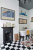 Original fireplace with framed poster and freestanding bath in Yorkshire home England UK