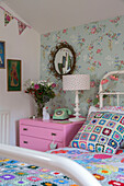 Colourful crochet cushion with rotary dial telephone at bedside in Victorian cottage Kidderminster Worcestershire England UK