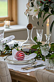 Christmas bauble on place setting with glassware and holly in Dorset farmhouse UK