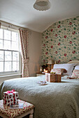 Christmas presents on double bed with floral wallpaper in Georgian cottage Liverpool UK