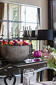 Large bowl of roses on console table with mirror in detached Sussex country house UK