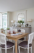 White painted wicker chairs at wooden dining table in detached Sussex country house UK