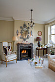 Gilt armchair at fireside with decorative mirror in London townhouse UK