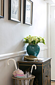 Cut flowers in turquoise ceramic vase on oriental cabinet in hallway of London home UK