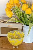 Yellow tulips with vintage radio and bowl in London home UK