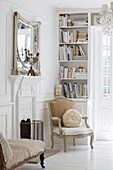 Cream armchairs and bookcase at fireside in Edwardian house Surrey UK