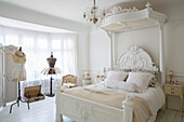 White canopy bed with mannequins in window of Edwardian house Surrey UK