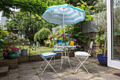 Striped parasol over garden furniture on terrace in Victorian townhouse garden South London UK