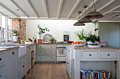 Metal pendant shades above island unit in grey fitted West Sussex farmhouse kitchen UK