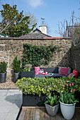 Graue Sitzgelegenheit mit Tulpen im Hinterhof eines Londoner Hauses UK