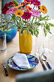 Michaelmas daisies in yellow vase at place setting in Arts and Crafts home Sevenoaks Kent UK