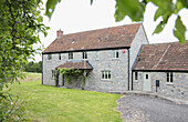 Steinfassade mit Ziegeldach und Veranda eines Bauernhauses in Somerset, UK