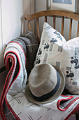 Sunhat and blanket with floral cushion on wooden chair in North London home UK