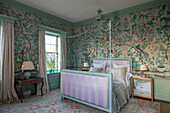 Antique Chinese silk wallpaper with metal framed bed and upholstered footboard in Georgian home Hertfordshire England UK