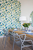 Grey chairs at wooden table with tulips and feature wall in newbuild home Cornwall UK