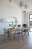 Grey dining chairs at table with large lamp and mirror in newbuild Cornwall UK