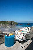 Chair and side table on balcony terrace with view to sea Cornwall UK