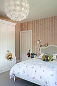 Doppelbett mit Sonnenhut und Spielzeug und großem Hängeschirm im Mädchenzimmer eines Hauses in London UK