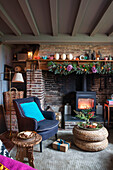 Armchair at fireside with wicker footstool in Norfolk cottage England UK