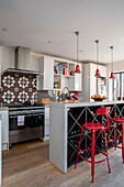 Red bar stools at breakfast bar/wine rack in kitchen of London family home UK