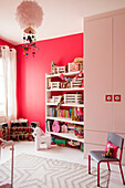 Kleiderschrank und Stuhl mit Spielzeug und Büchern auf Regalen im Spielzimmer eines Londoner Hauses UK