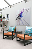 Zwei Sessel im Retrostil mit moderner Kunstleinwand in einem Londoner Haus UK
