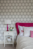 Geometric wallpaper ad pink accents in teen room of Victorian coach house West Sussex UK