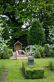 Armillary sphere and water feature in leafy garden of West Sussex home England UK