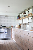 Regal aus Gerüstbrettern über Schubladen aus gekalkter Eiche mit Edelstahlherd in einer Küche in Surrey UK