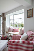 Erkerfenster und antiker Sessel in rotem Karo mit Weidenkorb in einem Bauernhaus in Surrey UK