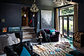 Purple armchair and gold curtains in split living room painted Off Black Welsh barn conversion UK