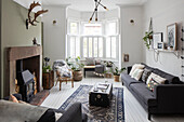 Erkerfenster mit Sofa und Wand in 'Lichen'-Kaminumrandung aus alten Steintorpfosten in Cumbria, Vereinigtes Königreich