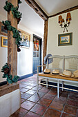 Sunhats on bench in terracotta tiled hallway in Norfolk farmhouse UK