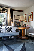 Cowhide cushions on daybed with striped curtains in Norfolk farmhouse UK