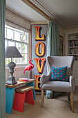 Single word 'LOVE' with painted side stools and upcycled chair ate window in Grade II listed farmhouse Bodmin Cornwall UK