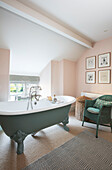 Clawfoot bath and wicker chair in window with walls in Pink Ground Grade II listed farmhouse Bodmin Cornwall UK