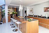 Chrome bar stools at wooden island unit in kitchen extension of London home UK