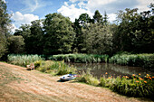 Ruderboot und Bank im Flussgarten eines Hauses in Surrey, Großbritannien