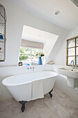 Kleine freistehende Badewanne an einer Dachgaube in einem Landhaus in Surrey, Großbritannien