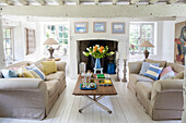 Schnittblumen auf Couchtisch mit Sofas in weißem Wohnzimmer in Surrey Cottage UK