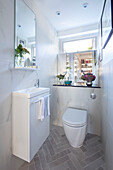 Small cloakroom with Carrara porcelain wall tiles and Rustic Grey herringbone Metro floor tiles London UK