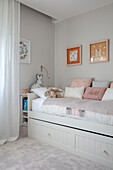 Tagesbett mit grauem Bezug und pastellrosa Kissen im Jugendzimmer London, UK